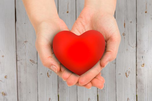 Hand showing heart against wooden background