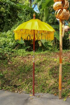Decoration of Hindu temple complex Batukaru on Bali island in Indonesia. Yellow and white decorative umbrellas line the path for believing visitors. Colorful fabric umbrellas with decorative fringes.