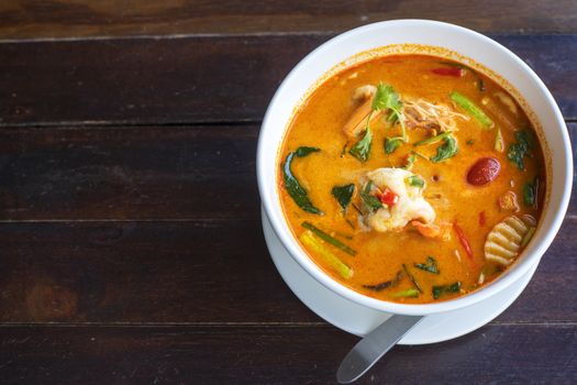 Tom Yam kung Spicy Thai soup with shrimp in white bowl on wood table. With copy space for text or design.
