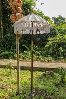 Decoration of Hindu temple complex Batukaru on Bali island in Indonesia. Yellow and white decorative umbrellas line the path for believing visitors. Colorful fabric umbrellas with decorative fringes.