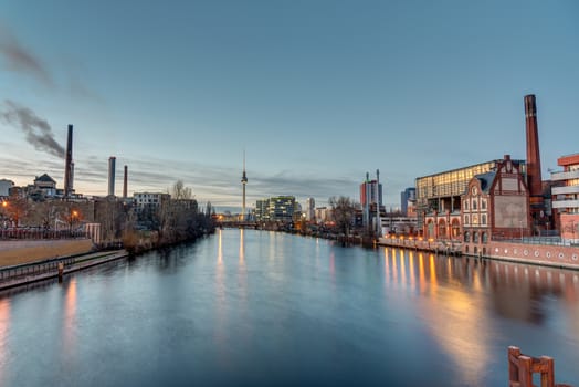 The river Spree in Berlin at dusk with industry buildings and the Fernsehturm in the back