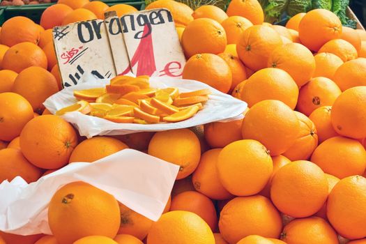 Oranges for sale at a market with some slieces on a plate