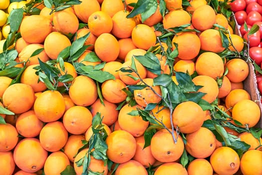 Fresh ripe oranges with green leaves for sale at market