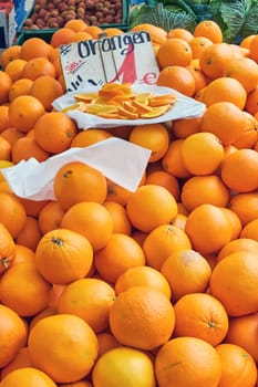 Tangerines for sale at a market with some pieces on a plate