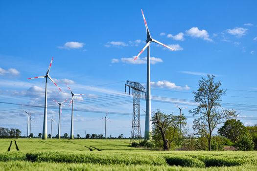 Overhead power lines and wind engines on a sunny day seen in Germany