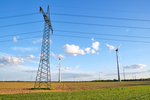 Electricity pylon with overhead lines and wind turbines seen in Germany