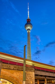 Commuter train and the famous Television Tower in Berlin at dusk