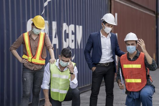 group people worker is wearing protection mask face and safety helmet and wearing suit safety dress With background of container cargo warehouse. Concept of industry worker operating.