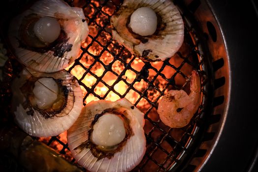 Barbecue grilled scallop seafood cooking on hot flaming grill.