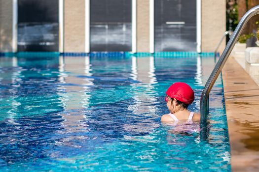 Child taking rest at the edge of swimming pool after swimming training.