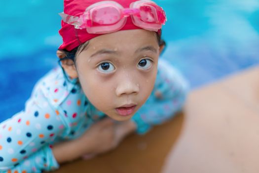 Asian girl at the edge of swimming pool.