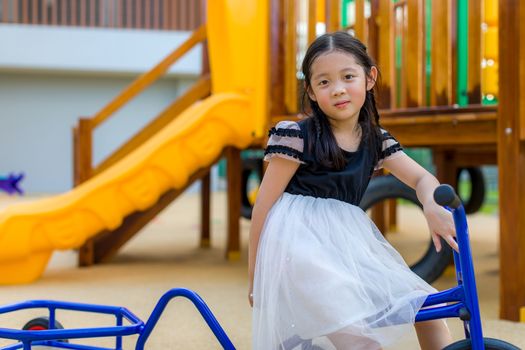 Asian child riding on bike in playground.