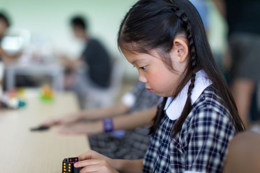 Asian child playing domino game on table.