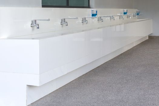 Long row of water tap and sink in school.