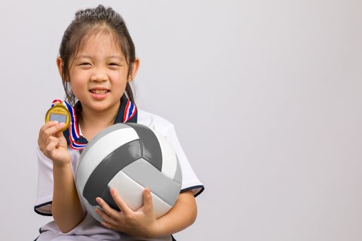 Kid holding ball and gold medal, studio shot, isolated on white.
