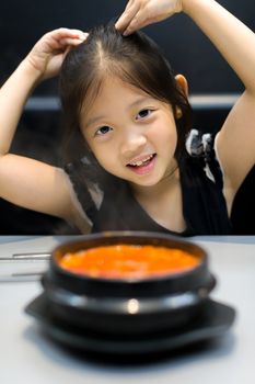 Asian kid with traditional Korean Kimchi soup.