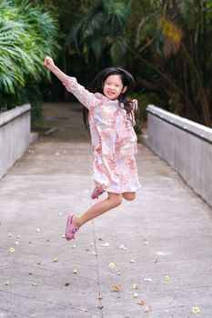 Asian kid jumping with fun and happiness outdoor park.