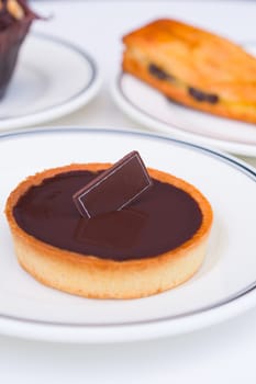 Pastry snack, chocolate tart dessert in white plate.