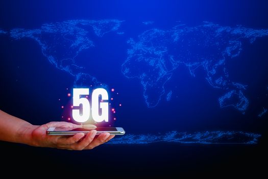 Hight speed internet concept. Human hand holding Smartphone and text 5G on blue technology background with copy space. Internet connection and communication around the world.