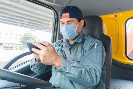 Close-up photos of Asian truck drivers wearing masks to protect against dust and the spread of the flu. Covid 19. Inside the car front.He is using a smartphone to communicate.White screen smartphone