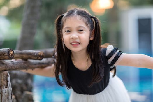 Asian child smiling at outdoor swimming pool.