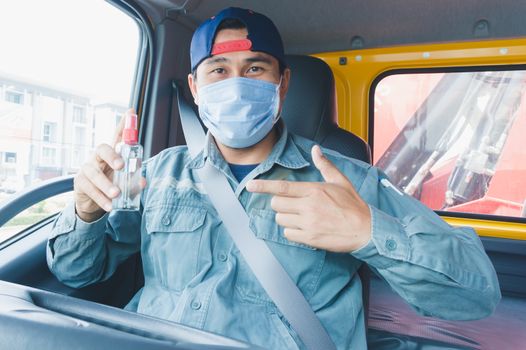 Close-up photos of Asian truck drivers wearing masks to protect against dust and the spread of the flu. Covid 19. Inside the car front.He carried an antiseptic and pointed his finger.