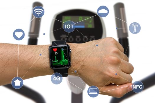 Concept of smart watch monitoring heart rate application while exercising with elliptical machine.