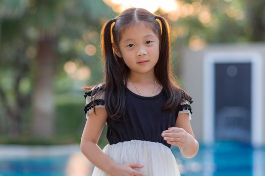 Asian child smiling at outdoor swimming pool.