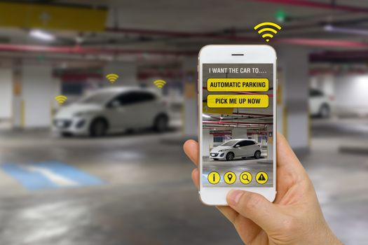 Concept of app on smartphone controlling self-driving car to park in parking lot.