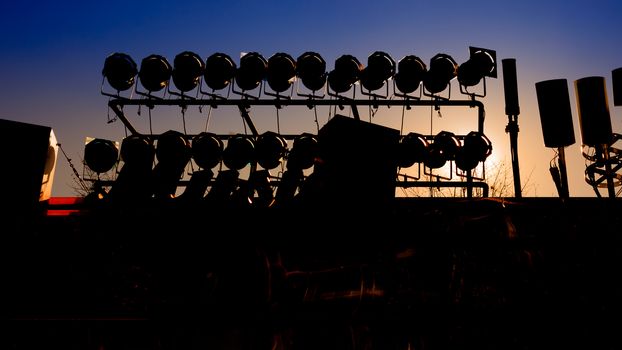 Background of silhouette of concert stage with blue sky and sun light.
