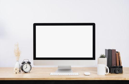 Mockup Blank screen desktop computer and decorations on wood table and white wall background.