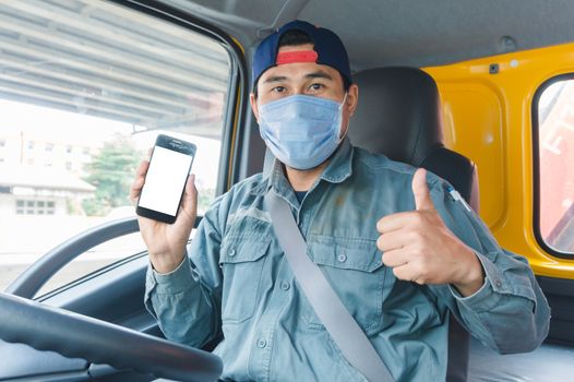 Close-up photos of Asian truck drivers wearing masks to protect against dust and the spread of the flu. Covid 19. Inside the car front.He is using a smartphone to communicate.White screen smartphone