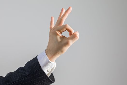 Concept of agreement showing by hand OK sign of businessman in suit, isolated on white, studio shot.