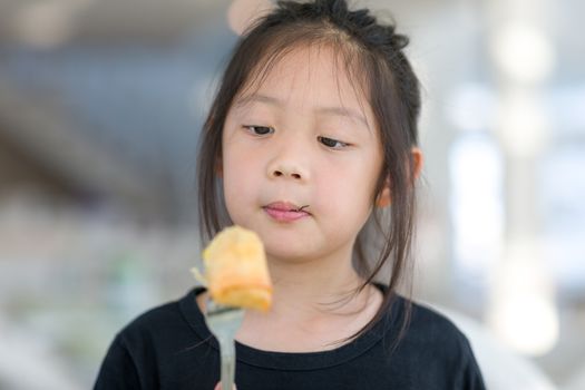 Cute Asian child enjoy eating food, fried spring roll.