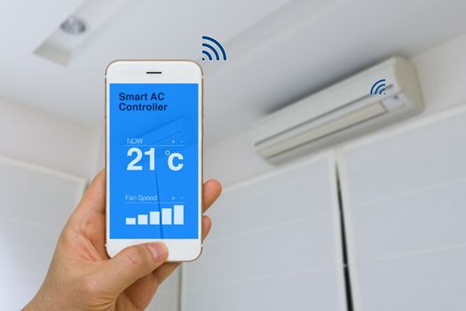Concept of IOT, remotely controlling smart air conditioner with app on smartphone from distance.