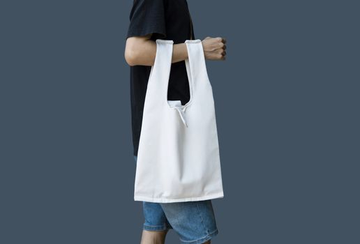 Man is holding bag canvas fabric for mockup blank template on gray background.