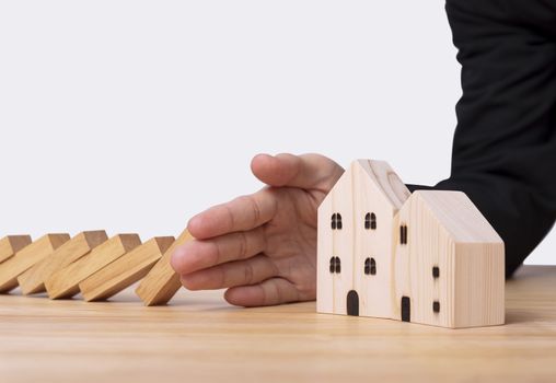 Hand stopping wooden block domino with home. concept home insurance.
