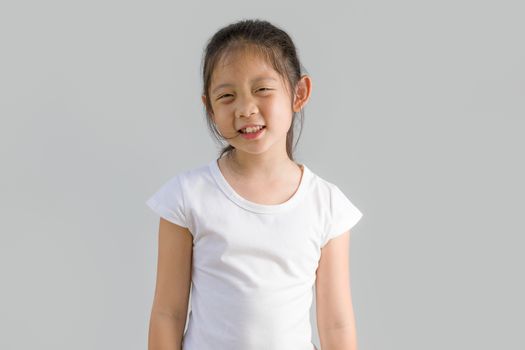 Studio shot of happy little Asian child, girl, with white t-shirt, isolated on white background.
