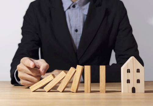 Hand stopping wooden block domino with home. concept home insurance.