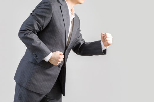 Studio shot of businessman in rush running forward, isolated on white background, illustrating success concept.