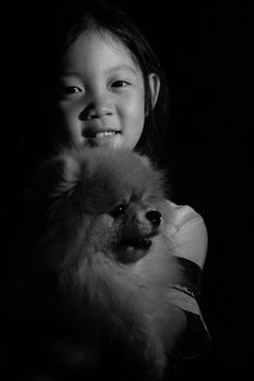 Black and white portrait of Asian child holding dog.