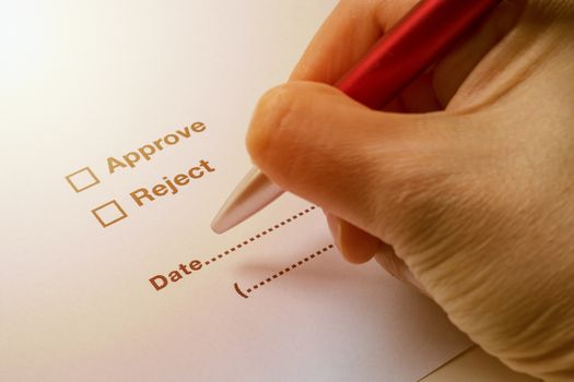 Business concept illustrated by hand holding pen to sign on approve or reject on document.