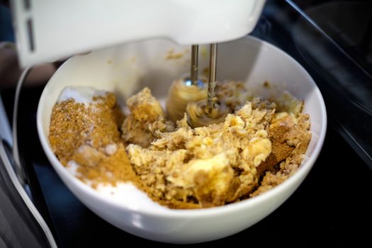 Mixer is mixing cookie ingredients in bowl.