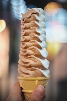 Cone of ice cream held by hand.