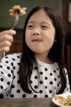 Child eating pastry snack with smile in vintage.