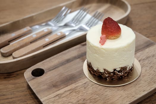 Fresh strawberry mousse cake dessert on wooden plate.