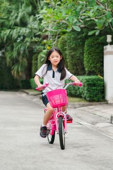 Asian child, girl, riding bicycle on street.