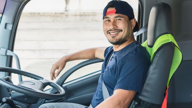 The Asian truck driver smiled happily inside the front of the truck. He is the owner of a shipping business that starts a new business and is growing.