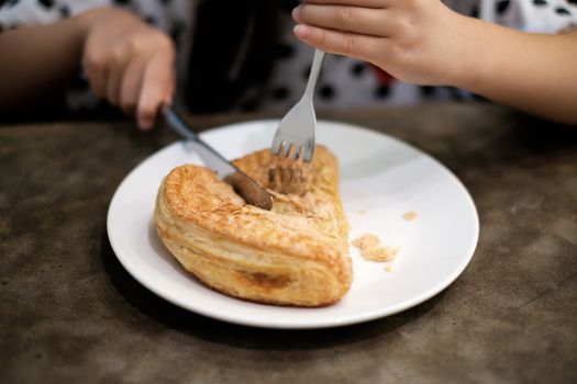Eating apple puff turnover pastry in dish.