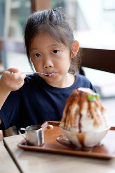 Happy Asian child enjoys eating Hawaiian shave ice frozen dessert.